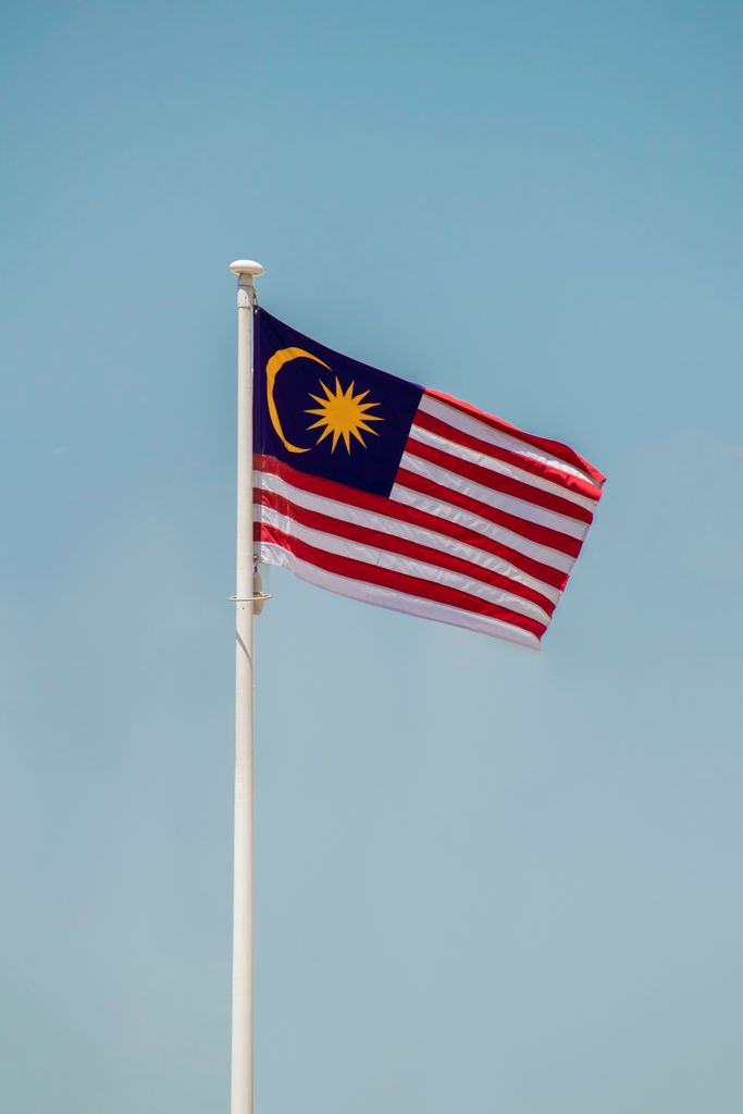 Malaysian national flag flying on a pole against a blue sky in Kuala Lumpur.